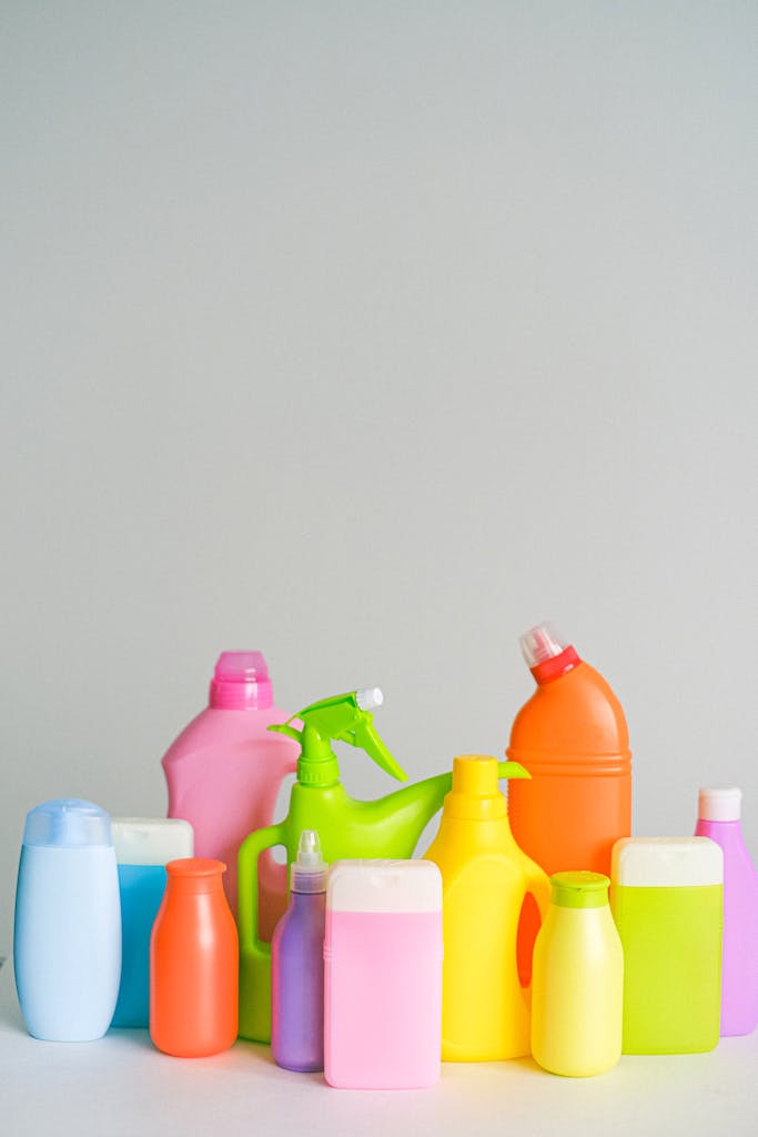 Collection of colorful plastic bottles with detergents sanitizers and cleaning products for everyday routine arranged on table against white background